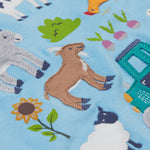 A close up of the Frugi kids bluebird farm life t-shirt  showing the cow, donkey, hen, goat, sheep, goose, tractor, sunflower, carrot, radish and a beetroot appliqué on light blue organic cotton fabric. 