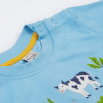 A close up of the Frugi kids bluebird farm life t-shirt  showing the shoulder popper fasteners for easy fitting and light blue neck trim with a yellow trim on the inside on light blue organic cotton fabric.