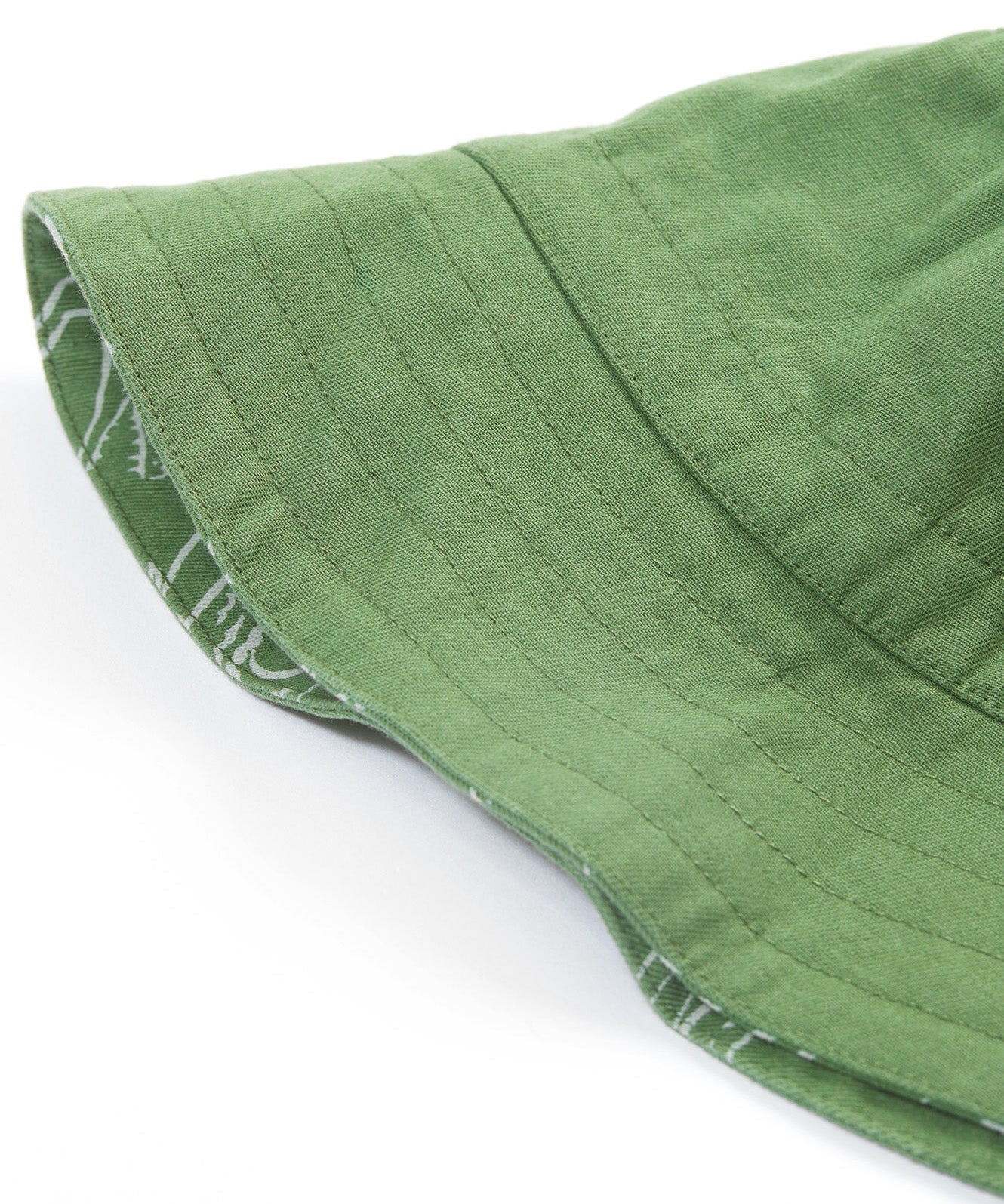 A close up of the Frugi kids green crocodile reversible hat. Showing the other side of the hat which is a plain green organic cotton fabric