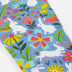 A close up of the Frugi kids bunny bounce libby leggings. Showing the multicoloured flower design with white bunnies on light purple organic cotton fabric