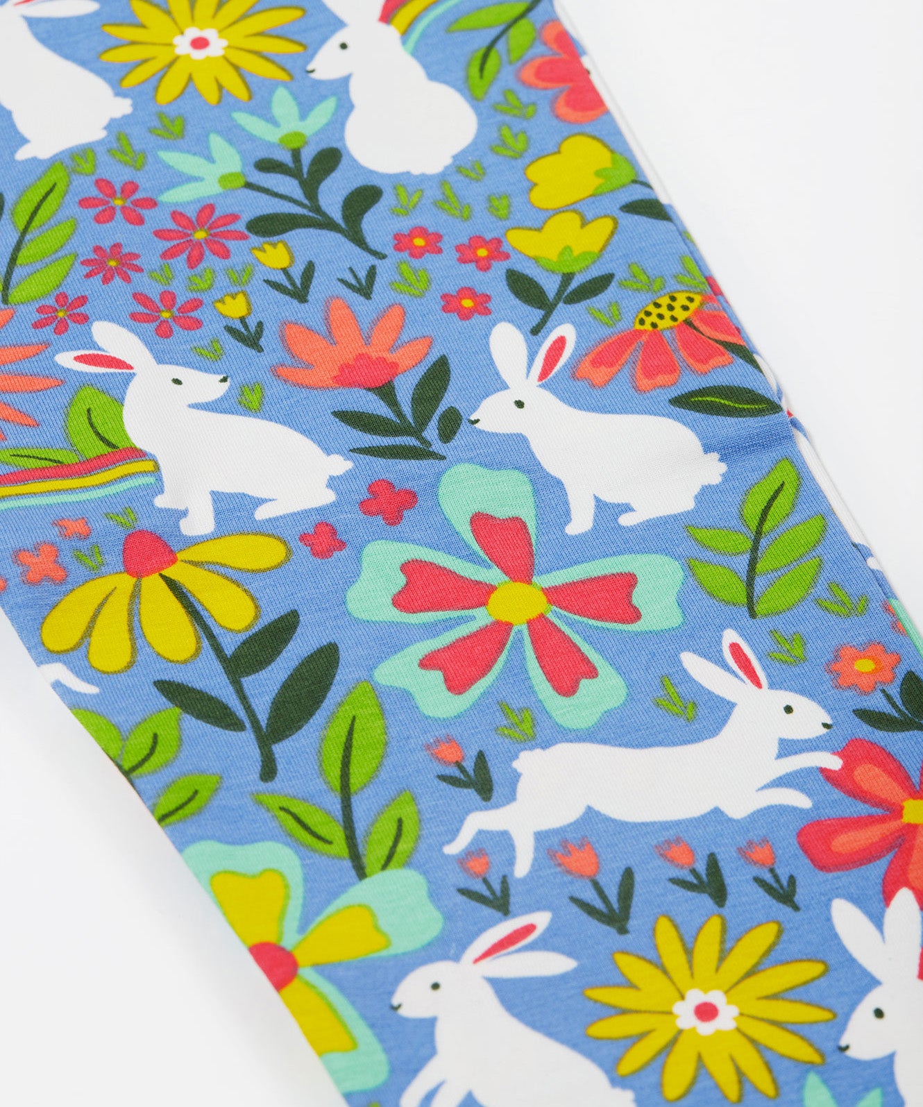 A close up of the Frugi kids bunny bounce libby leggings. Showing the multicoloured flower design with white bunnies on light purple organic cotton fabric