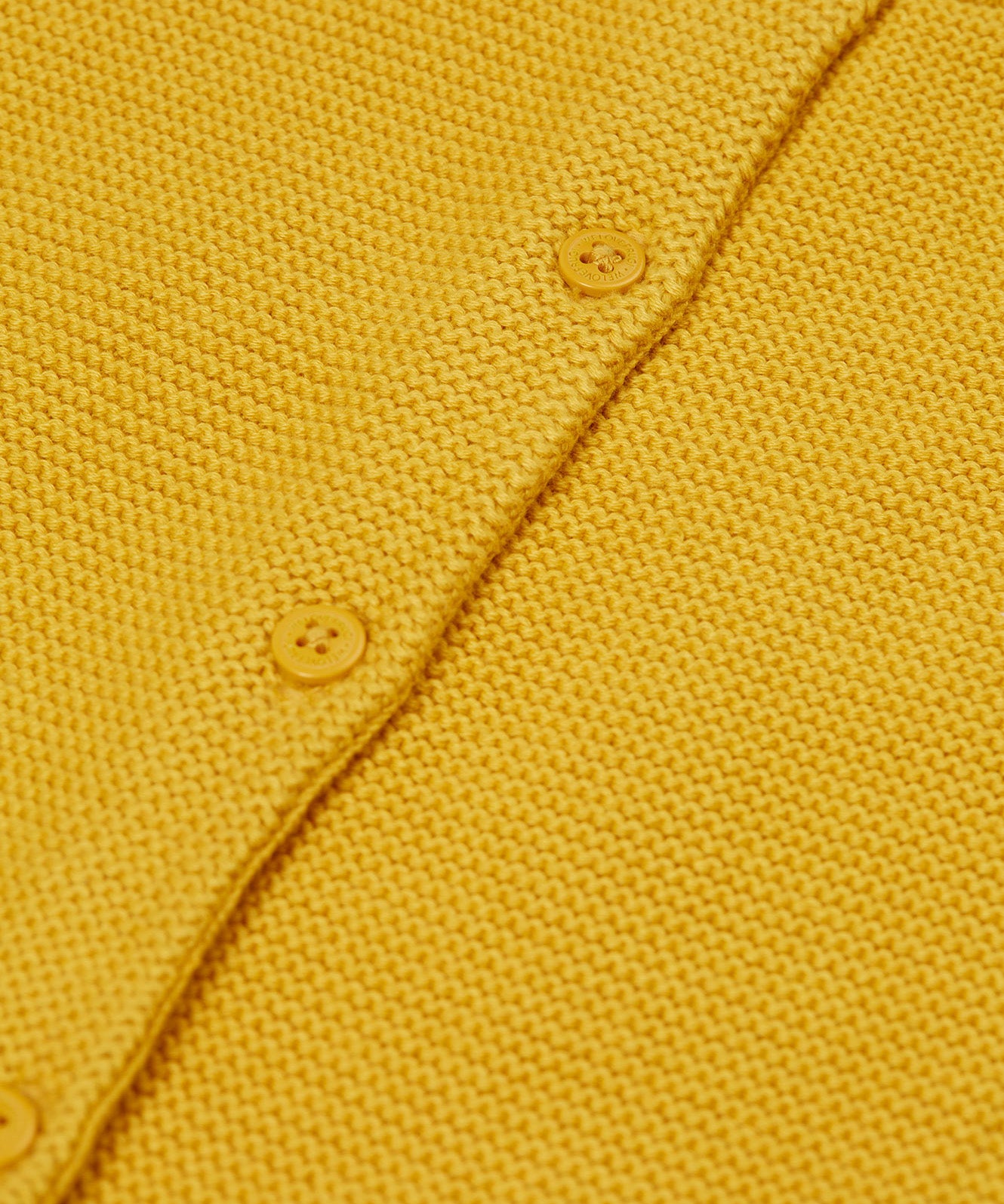 A close up of the Frugi yellow organic knitted cotton cardigan which features yellow buttons