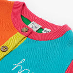 Close up of the Frugi kids Rose pocket cardigan, happy pen pot. Showing the button detail and pink neck trim on organic knitted fabric