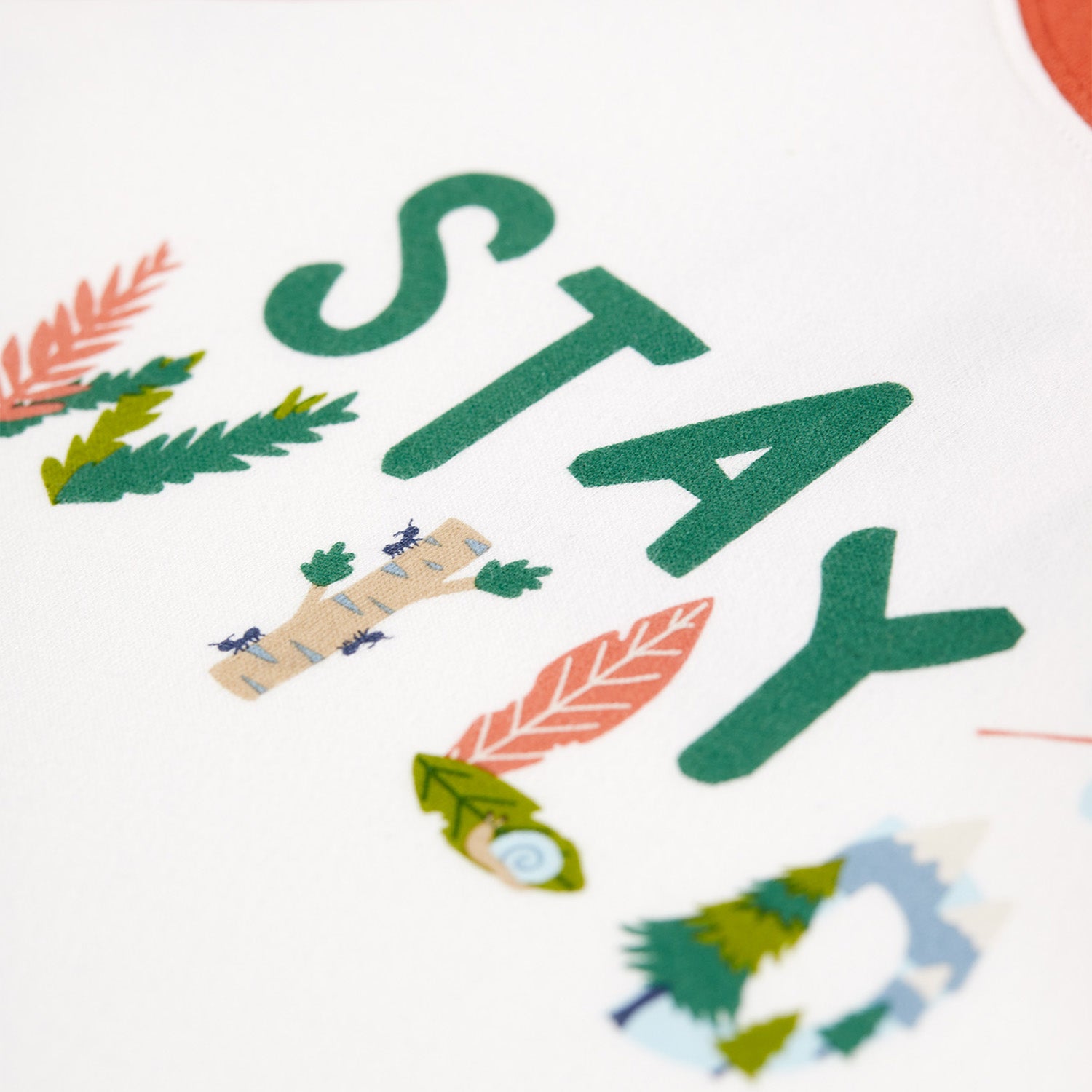 Motif and material detail on the Frugi Luke Raglan Top - Stay Wild / Paprika.