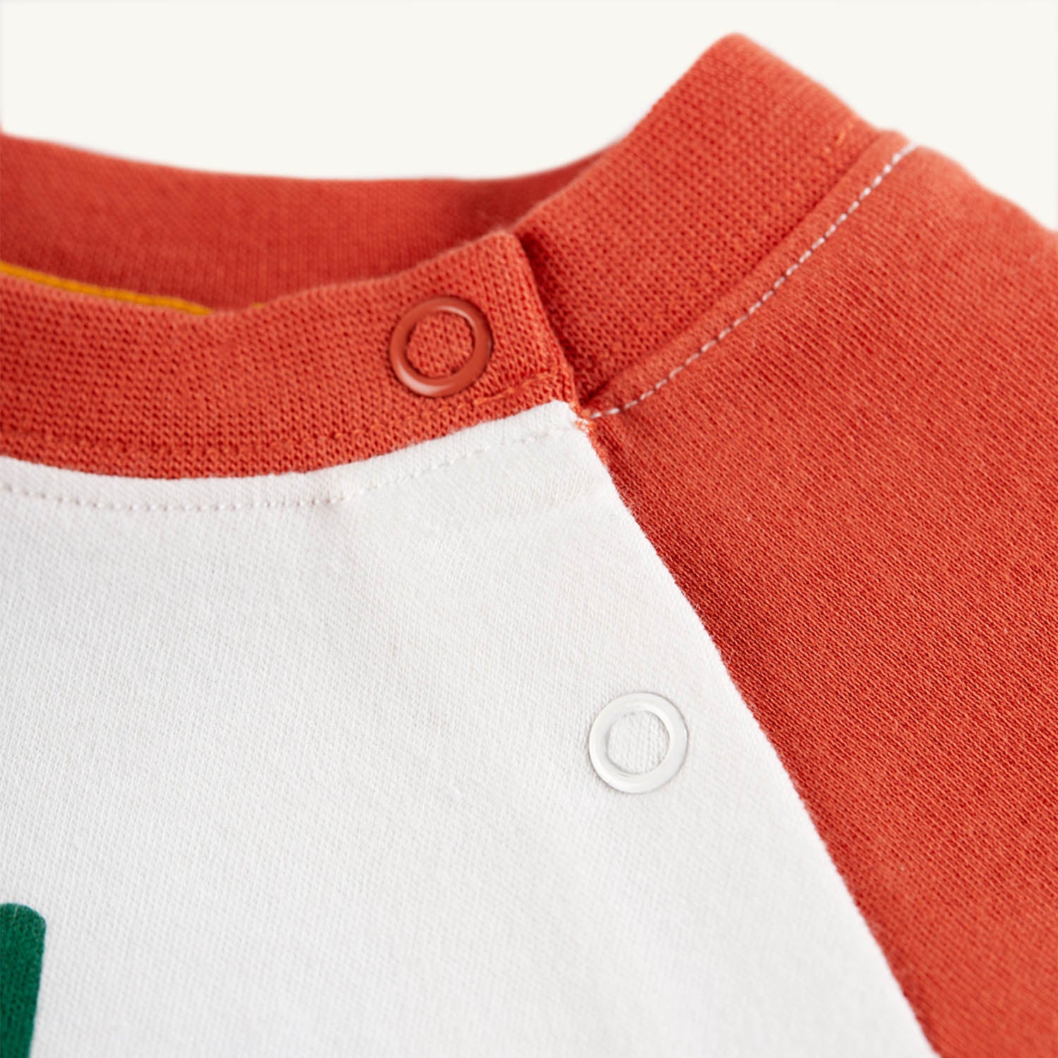 Neck fastener and material detail on the Frugi Luke Raglan Top - Stay Wild / Paprika.