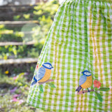 A close up of the embroidered bird applique detail on the bottom of the Frugi Children's Organic Cotton Macaw Gingham  Birds Zaria Dress 