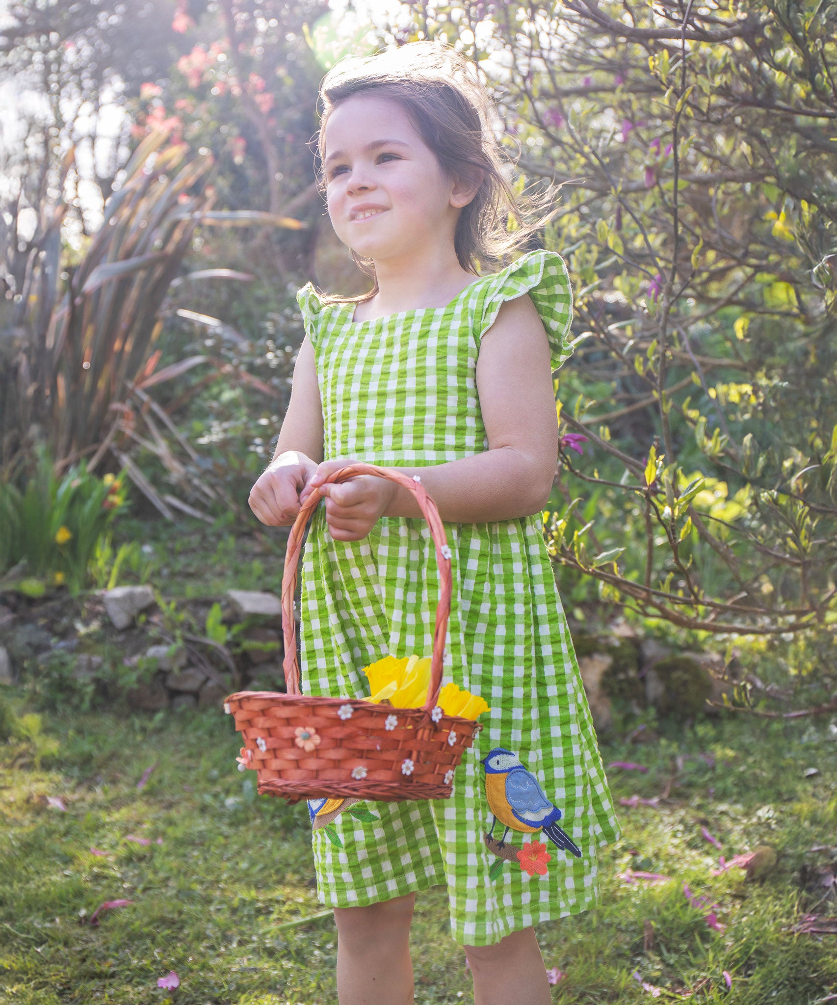 A child wearing the Frugi Children's Organic Cotton Macaw green and white Gingham Zaria Dress.