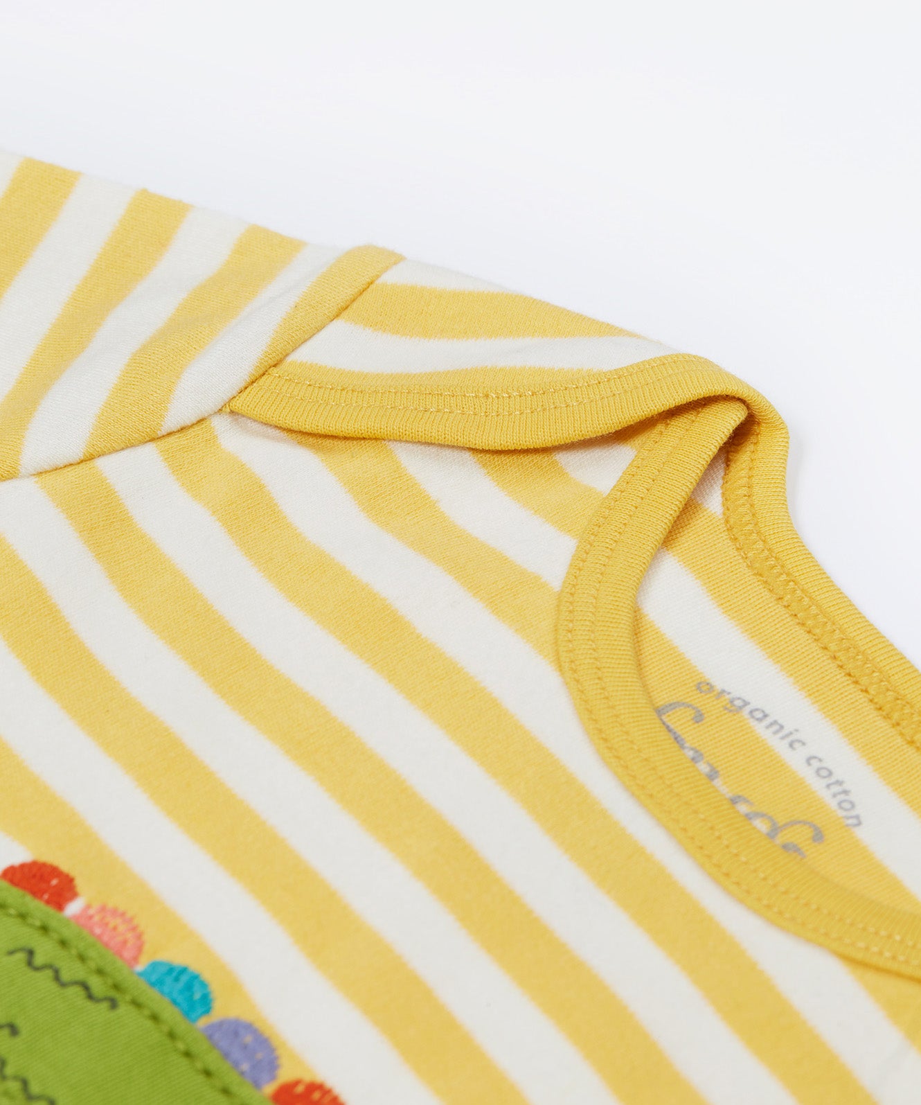 Close up of the Frugi kids crocodile rue romper. Showing the shoulder detail on yellow and white striped organic cotton fabric