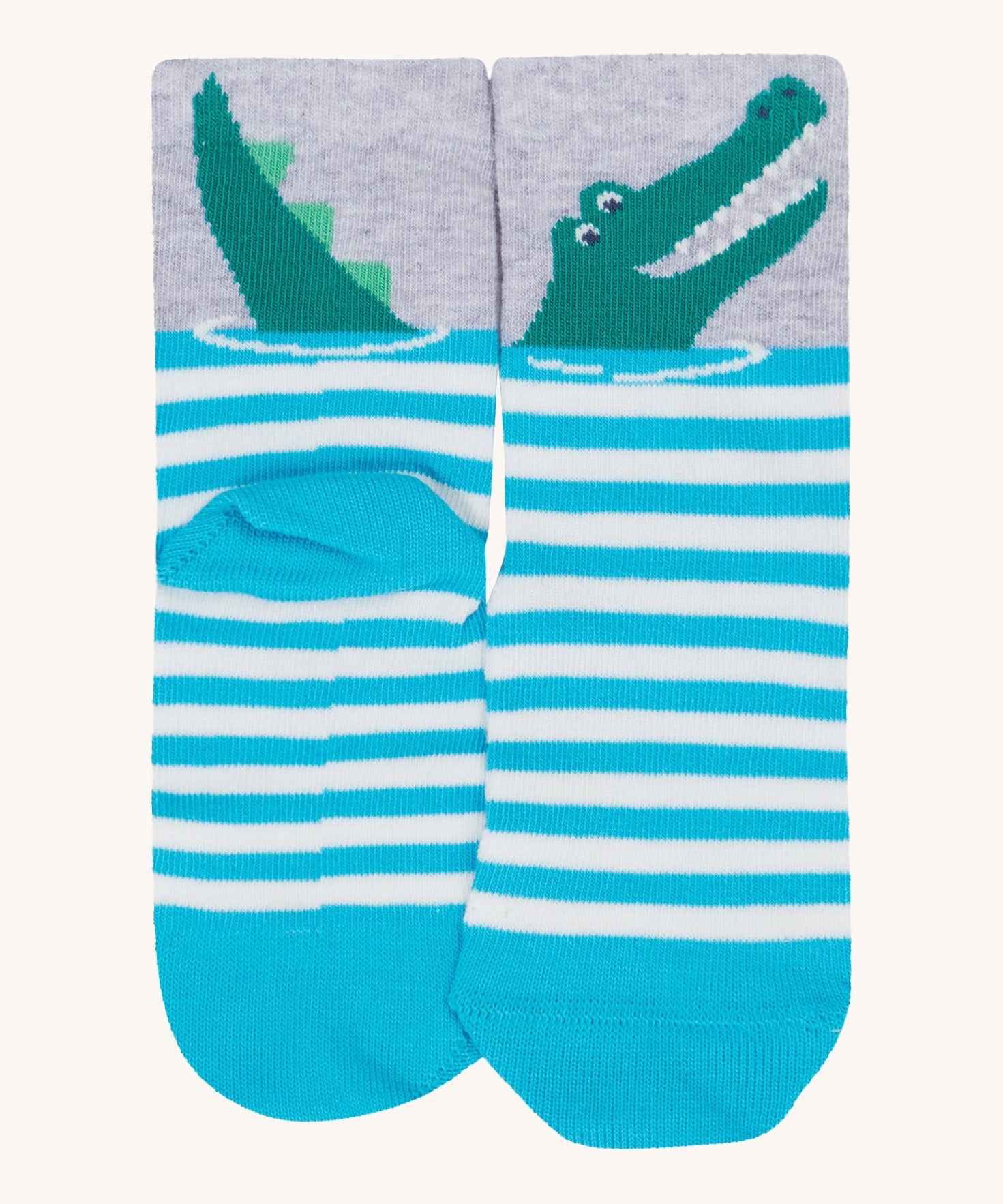 A close up of the Frugi crocodile sock. Showing the crocodile design on the light grey cuff on blue and white stripe organic cotton fabric