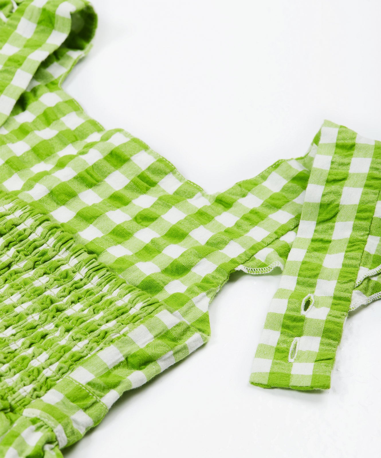 Close up of the Frugi kids macaw gingham birds dress. Showing the shoulder strap detail on green and white gingham organic cotton fabric.