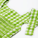 Close up of the Frugi kids macaw gingham birds dress. Showing the shoulder strap detail on green and white gingham organic cotton fabric.