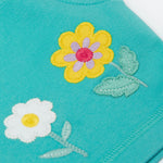 A close up of the shorts from the Frugi kids bee stripe outfit. Showing the flowers applique on a light blue organic cotton fabric