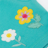 A close up of the shorts from the Frugi kids bee stripe outfit. Showing the flowers applique on a light blue organic cotton fabric