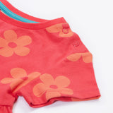 Close up of the Frugi kids flora fun koala tunic top. Showing the two popper fastener detail on the shoulder on light pink organic cotton fabric with pastel orange floral prints