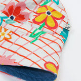 Close up of the Frugi kids hattie reversible hat - showing the white square with red lines and flower design with the denim detail on the flip side of the bucket hat on a organic cotton fabric