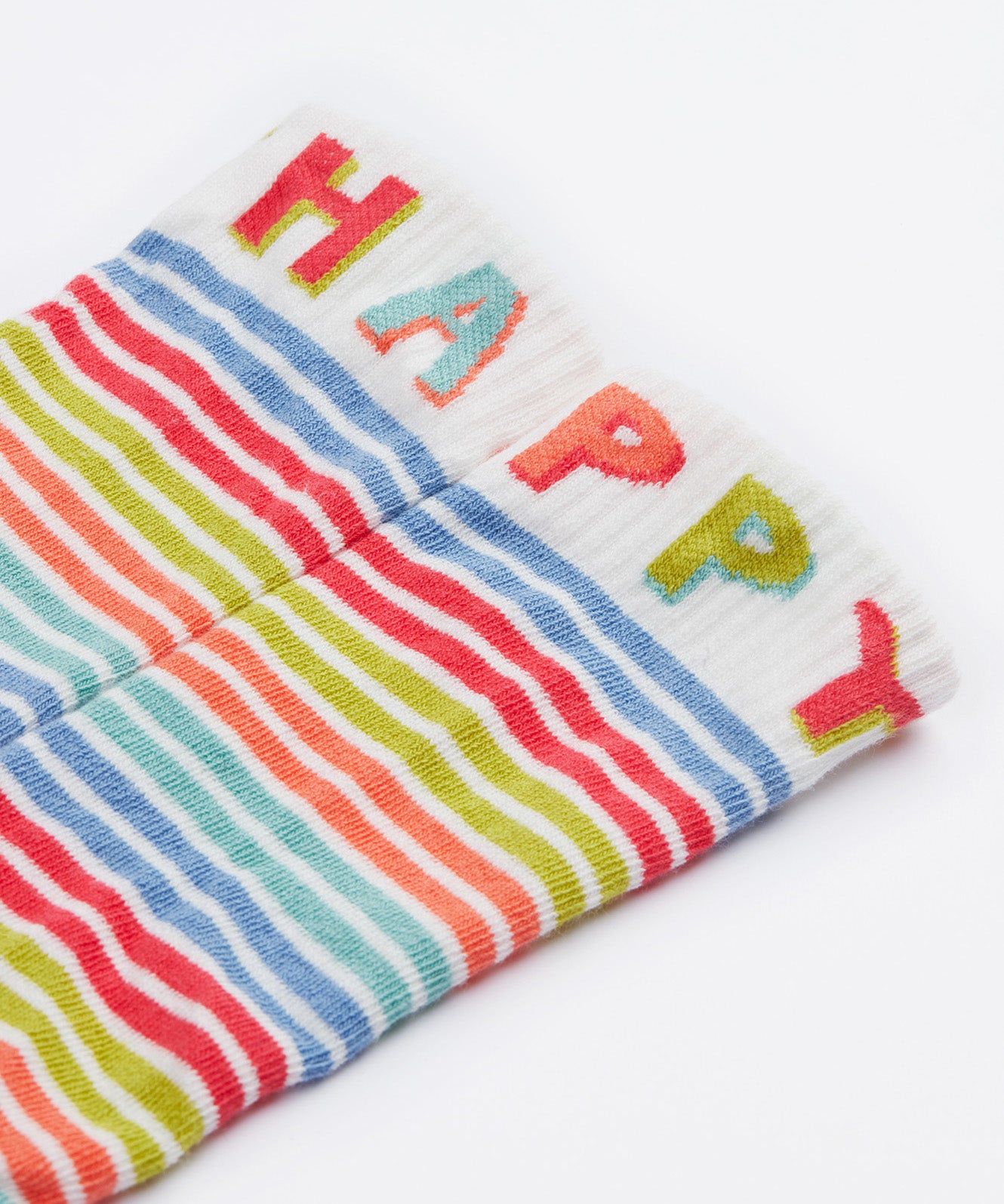 A close up of the Frugi kids hygge knee high sock. Showing the happy slogan on the white leg cuff on multicoloured striped organic cotton fabric