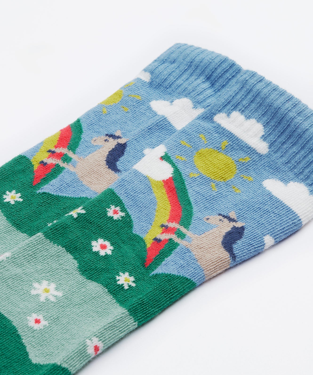 Close up on the Frugi kids hygge knee high sock showing horse in a field of daisies design on organic cotton fabric