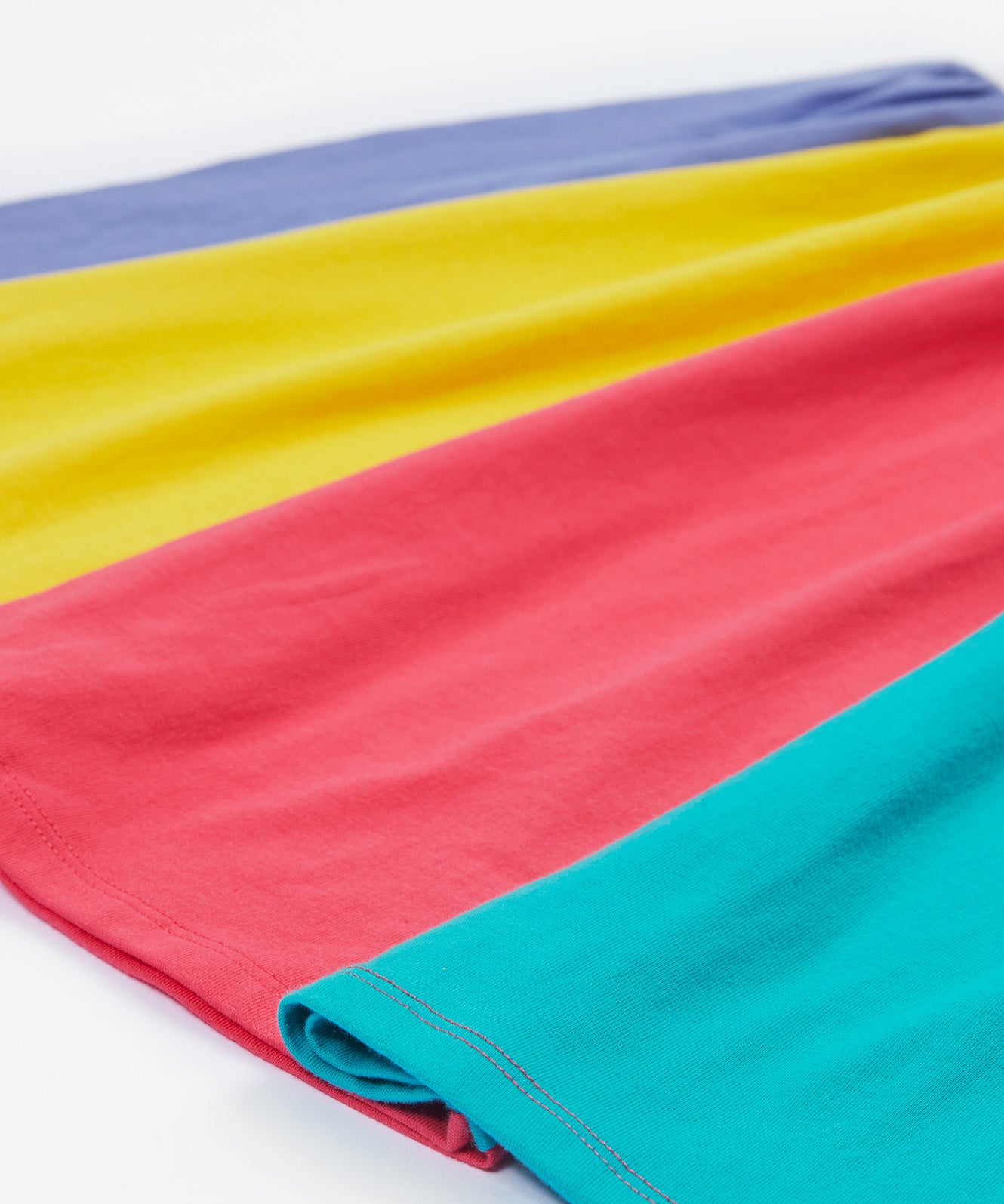 Close up of the Frugi kids jersey rainbow dress - showing the block rainbow bottom half on organic cotton fabric