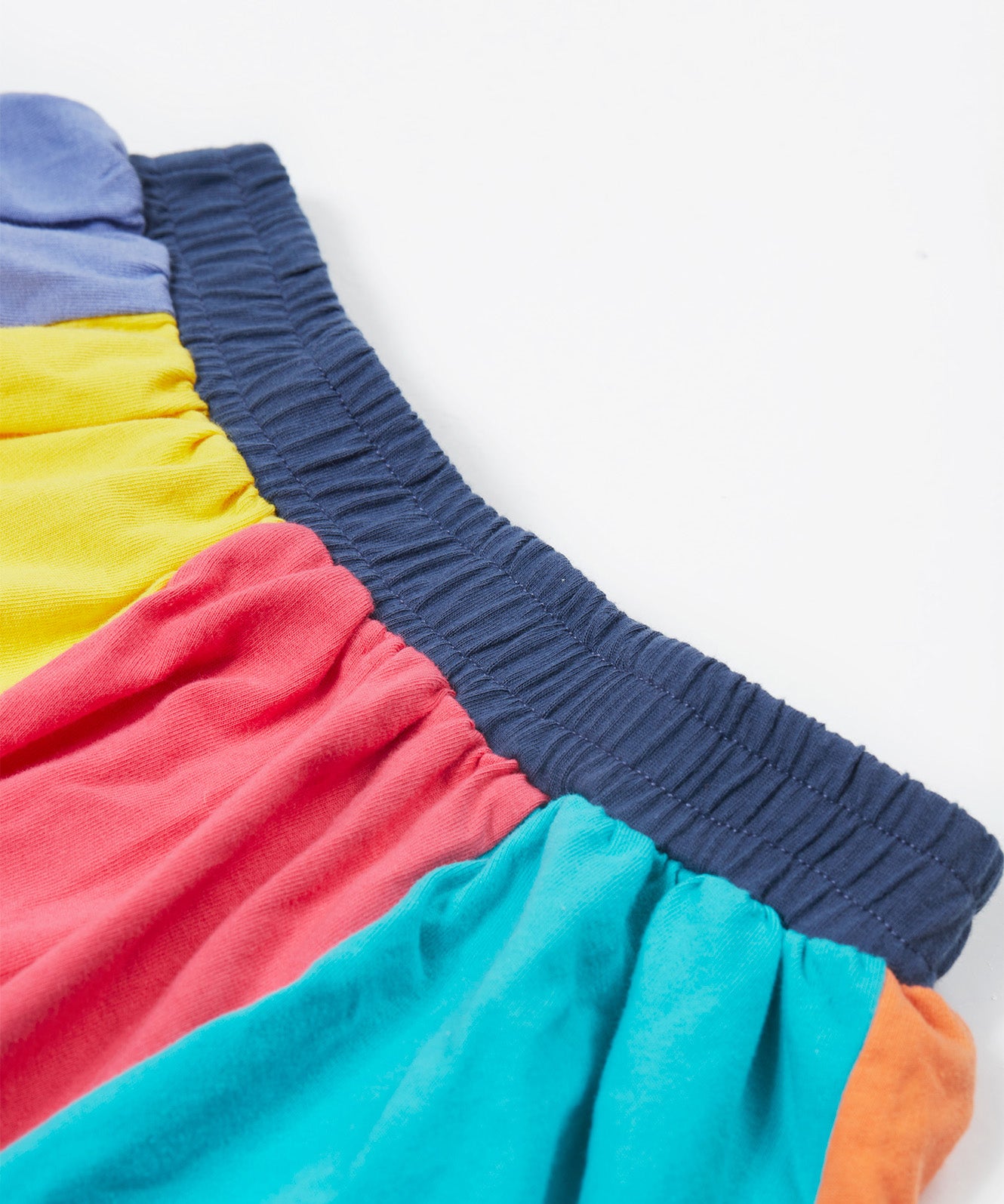 Close up of the Frugi kids rainbow jersey skit showing the navy elasticated waist band and rainbow colour block  panels on organic cotton fabric