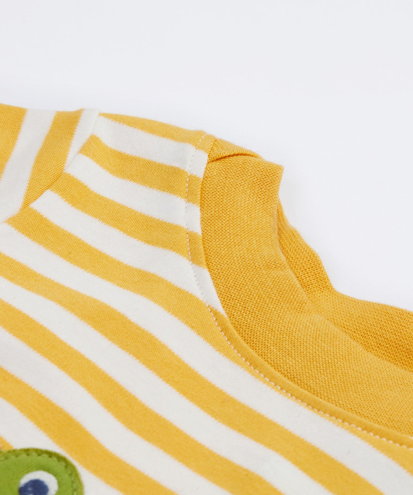 A close up of the Frugi kids wrap around crocodile outfit. Showing the yellow neck trim on yellow and white stripe organic cotton fabric