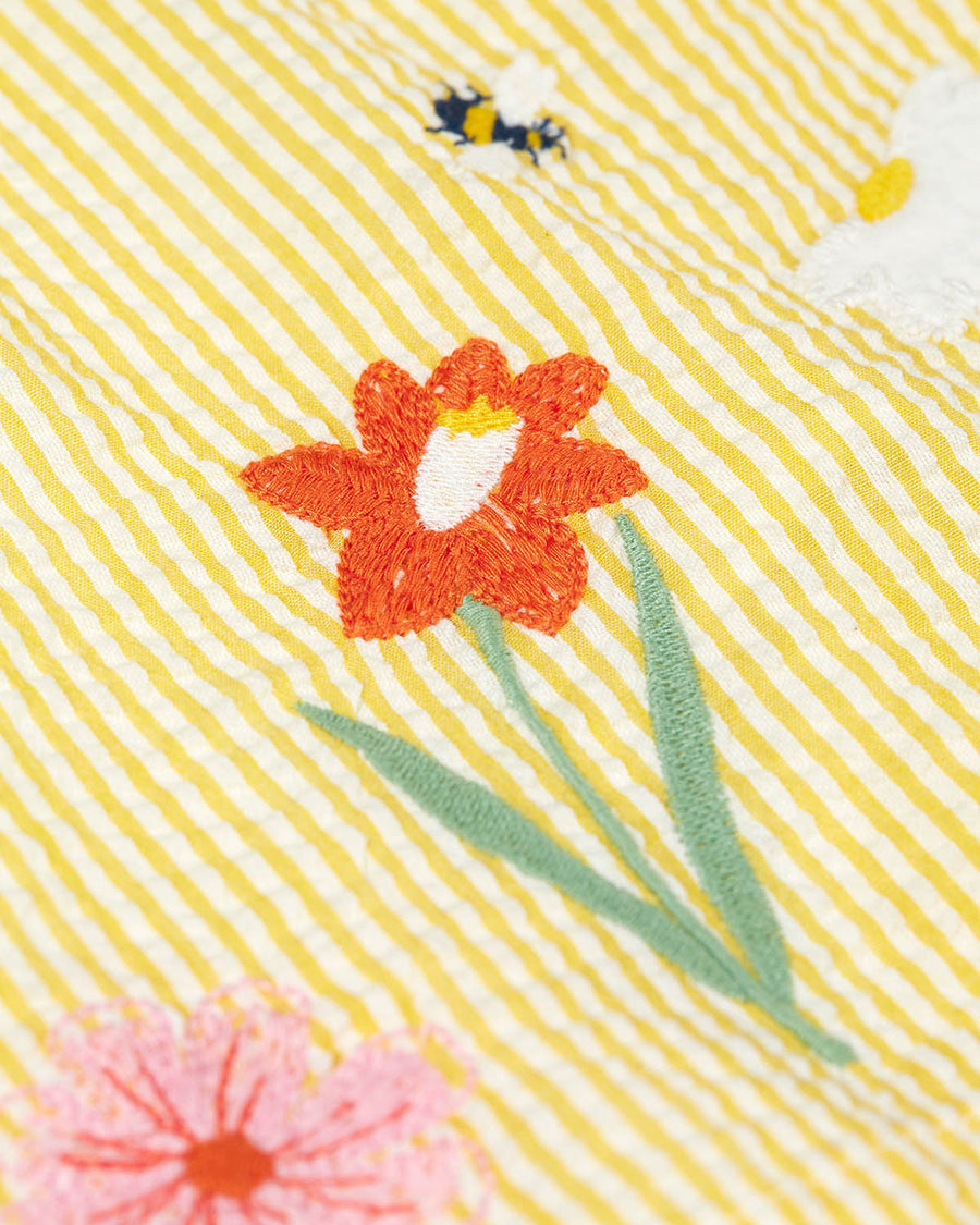 A closer view of the embroidered flowers and bee detail on the front of the Frugi Organic Cotton Devon Baby Body Dress - Flowers.