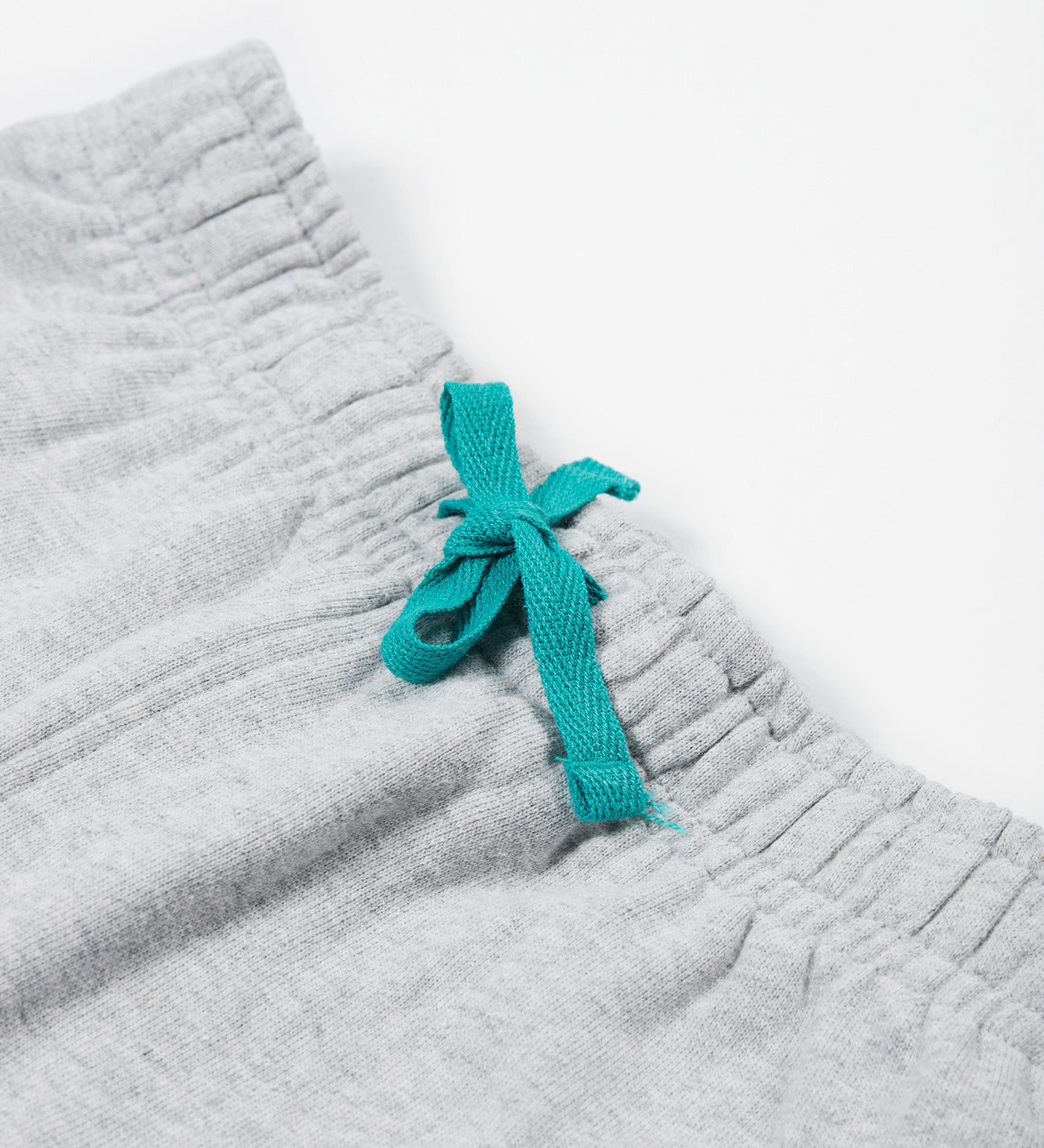 Close up of the Frugi kids jack appliqué joggers - Showing the  turquoise waist drawstring detail on grey organic cotton fabric