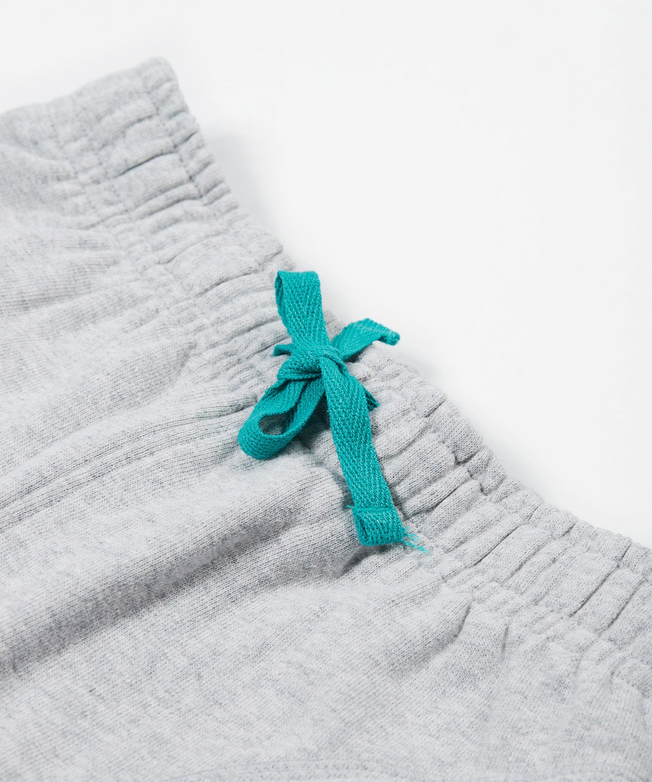 Close up of the Frugi kids jack appliqué joggers - Showing the  turquoise waist drawstring detail on grey organic cotton fabric