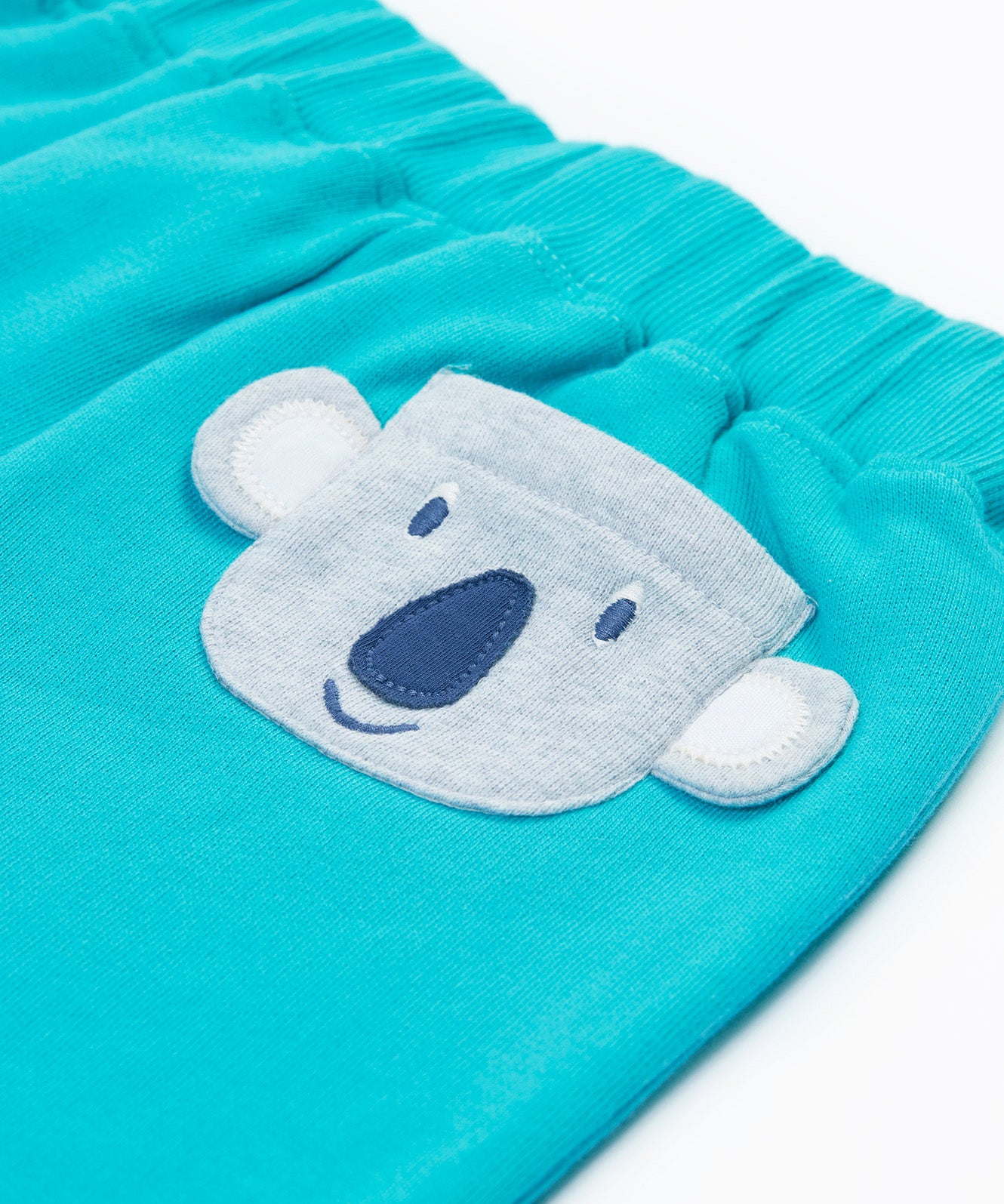 Close up of the Frugi kids koala shorts showing the grey koala back pocket detail on light blue organic cotton fabric