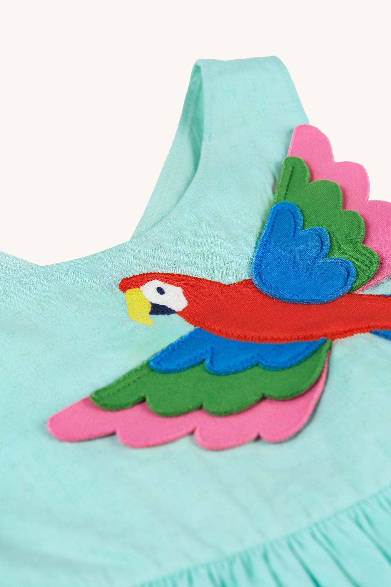  with a bright Macaw parrot applique on the front. On a cream background