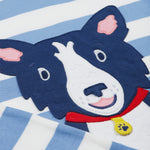 A close up of the Frugi kids Porth collie dog pyjama set showing the appliqué of a collie dog on blue and white striped organic cotton fabric