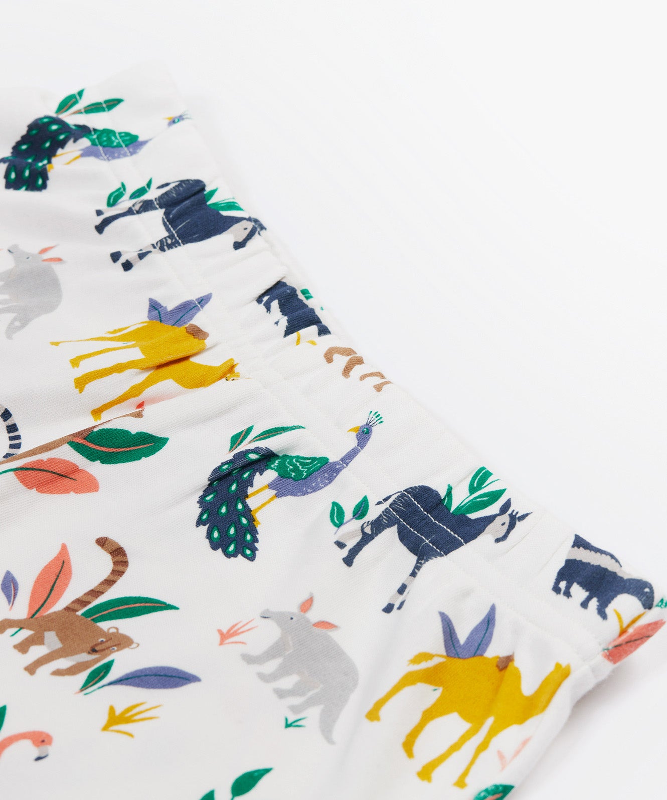 A close up of the Frugi kids snooze wildlife pyjama set showing the prints of different wild animals and elastic waist band on white organic cotton fabric