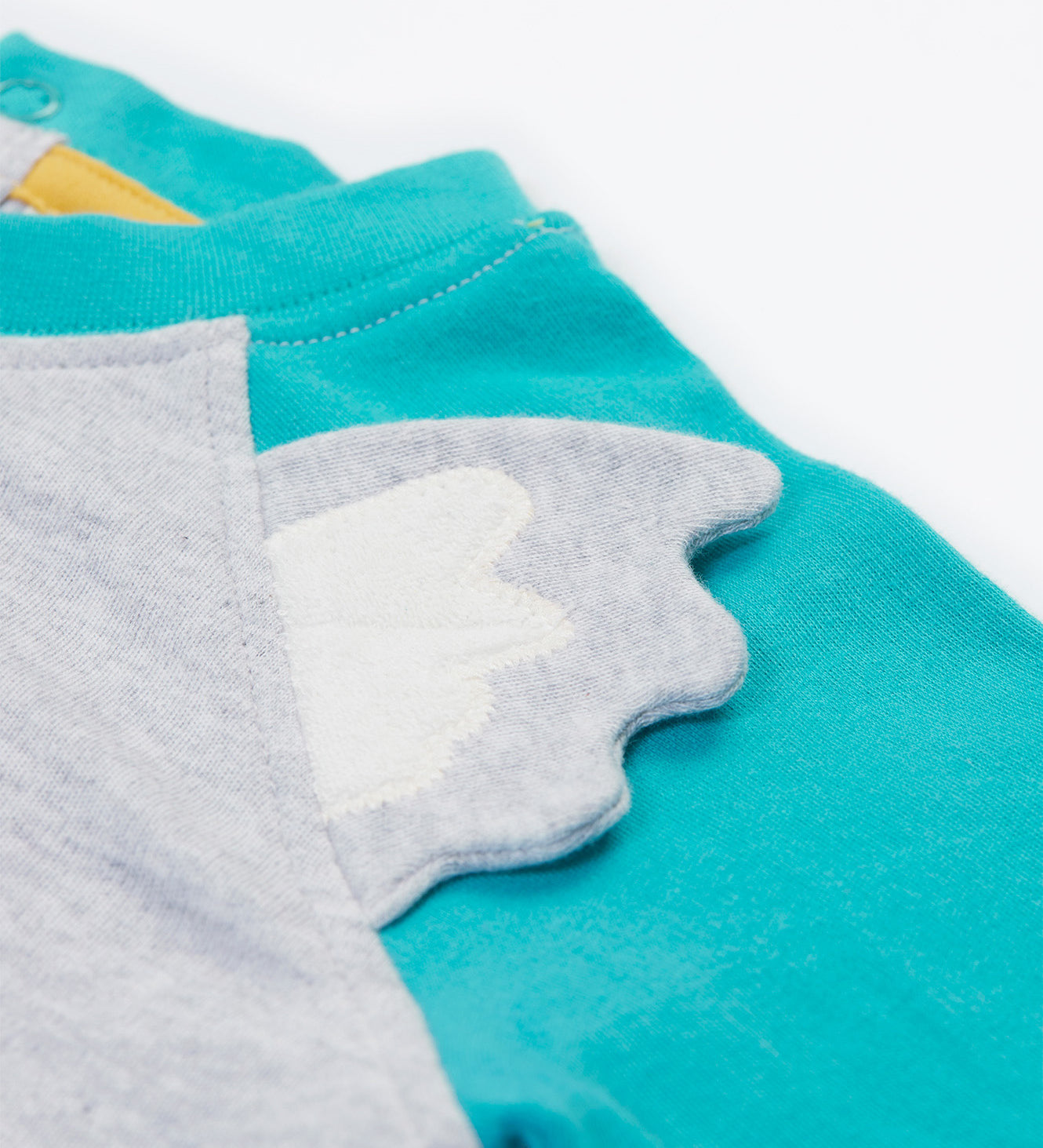 Close up of the Frugi kids koala raglan t-shirt. Showing the grey ears stitched loosely on the front panel on grey and blue organic cotton fabric