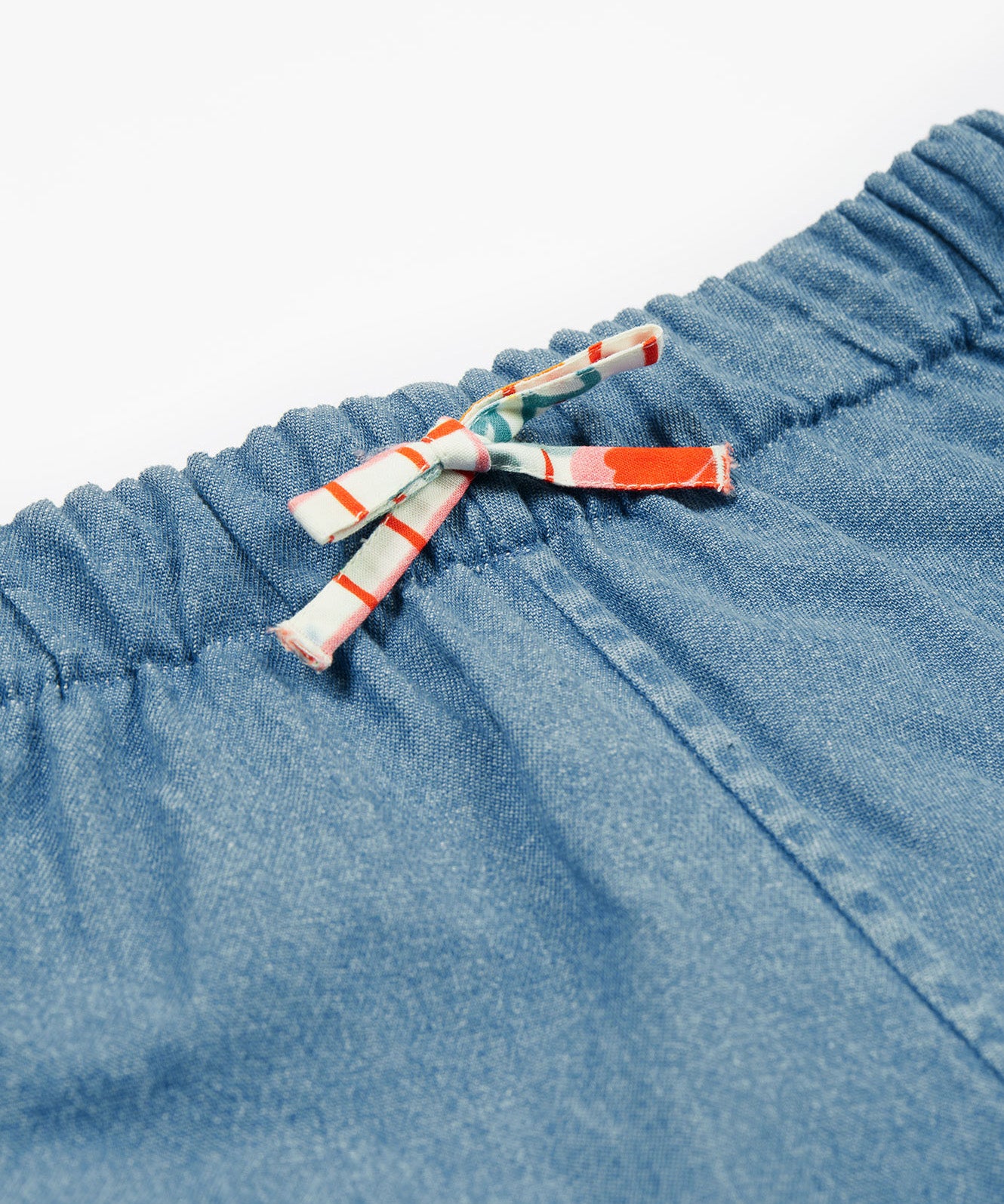 Close up of the frugi marigold reversible shorts, paint a floral / denim - GOTS organic cotton kids reversible shorts showing the denim and waist drawstring detail