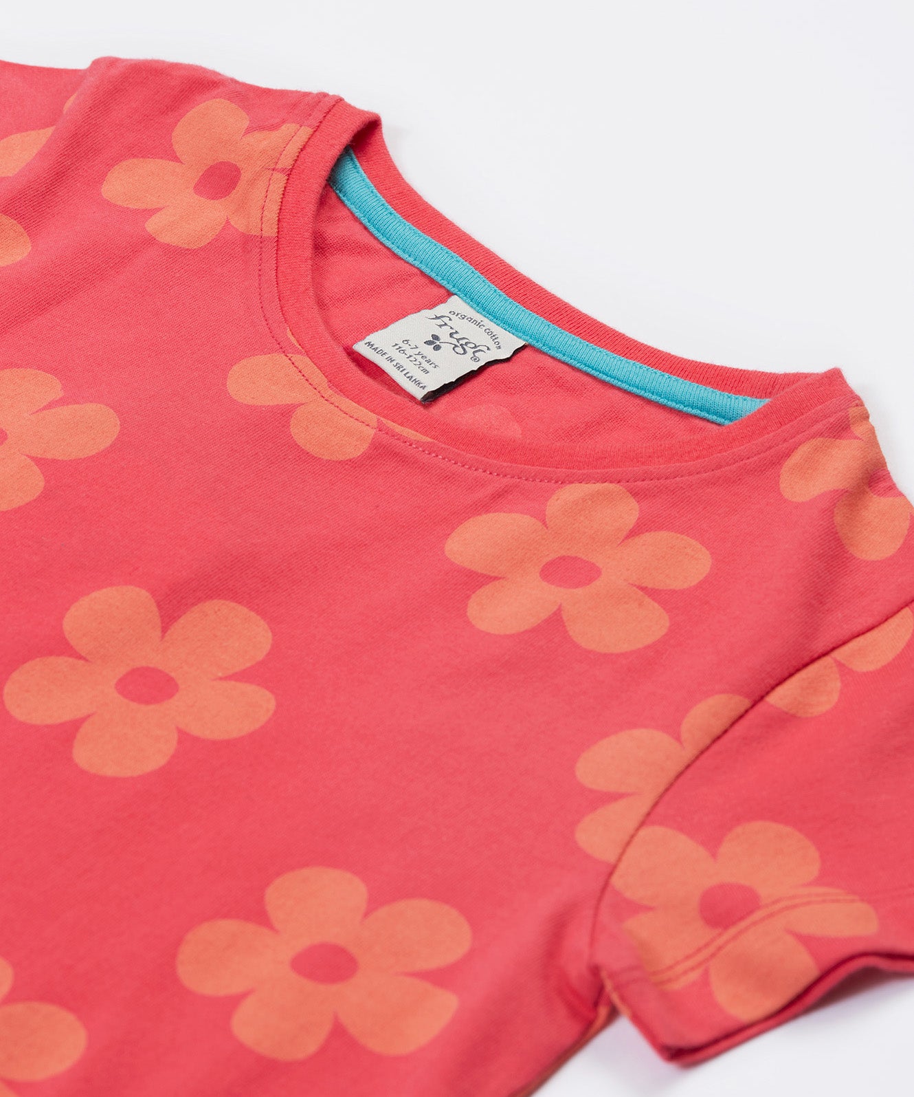 Close up of the Frugi kids flora fun koala t-shirt. Showing the neck detail with light blue trim on the inside on pink organic cotton fabric with pastel orange floral print