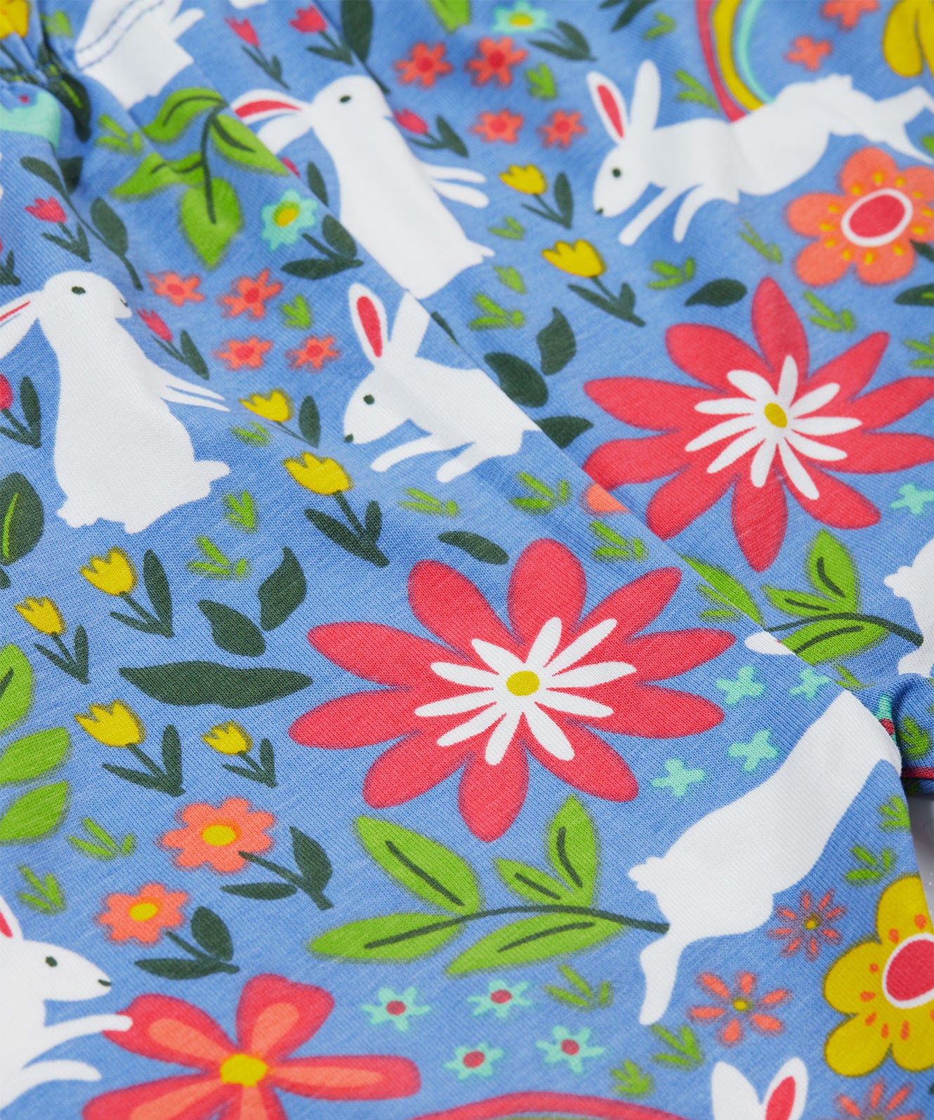 Close up of the Frugi kids watermelon iris bunny bottoms. Showing the different white rabbit and floral prints on light blue organic cotton fabric.