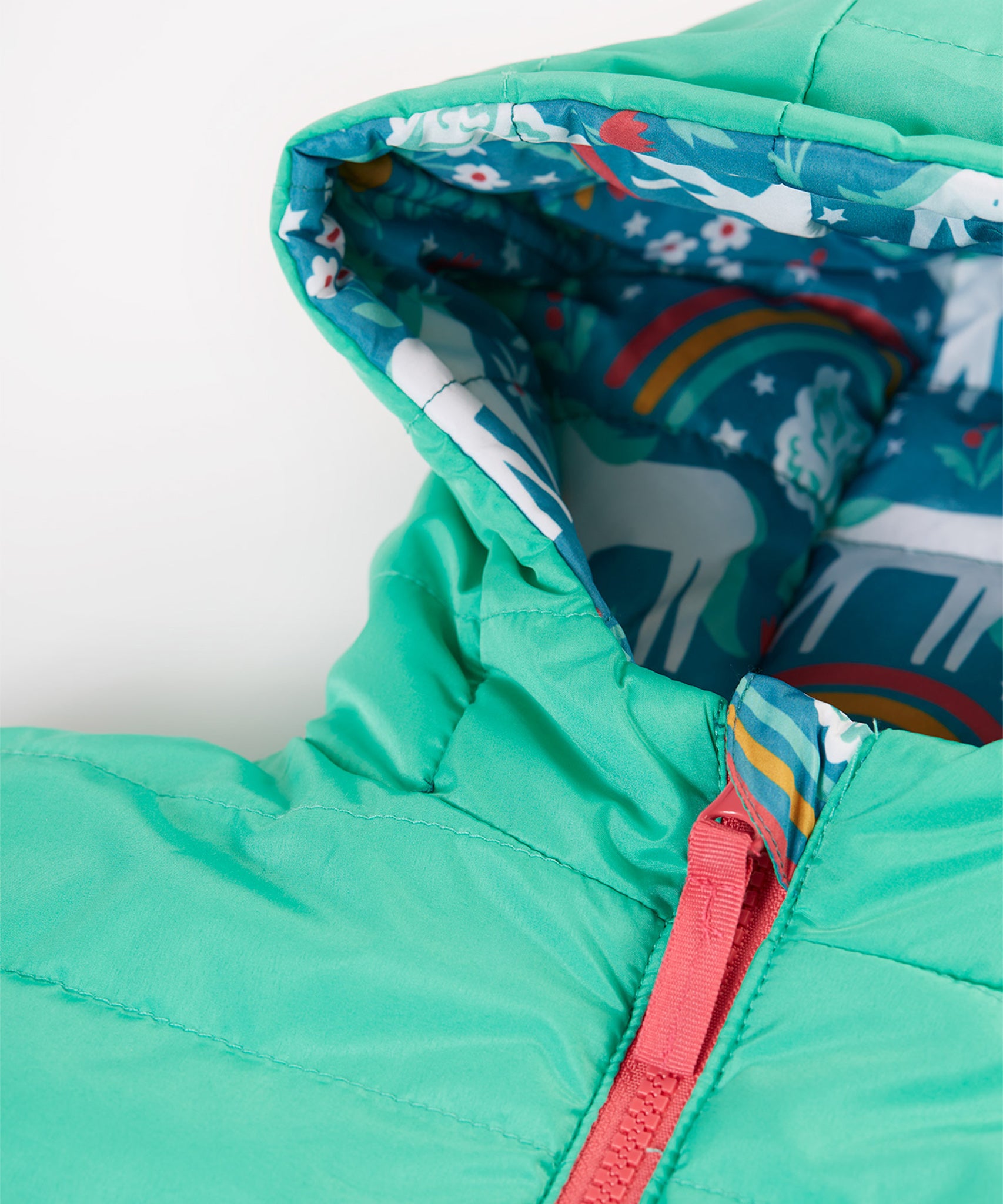 A child undoing the zipper on the Frugi Reversible Toasty Trail Jacket - Wild Horses. The turquoise side is shown in the image