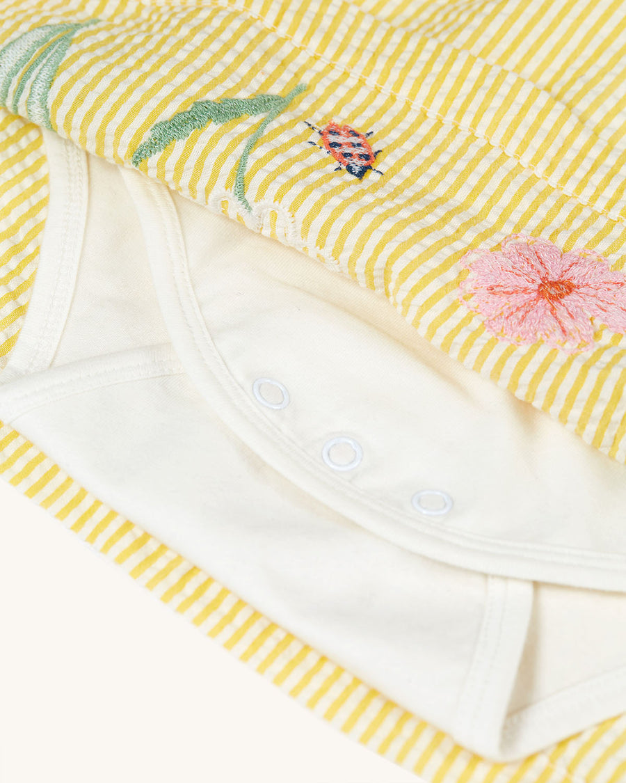 The white body suit inside the Frugi Organic Cotton Devon Baby Body Dress - Flowers