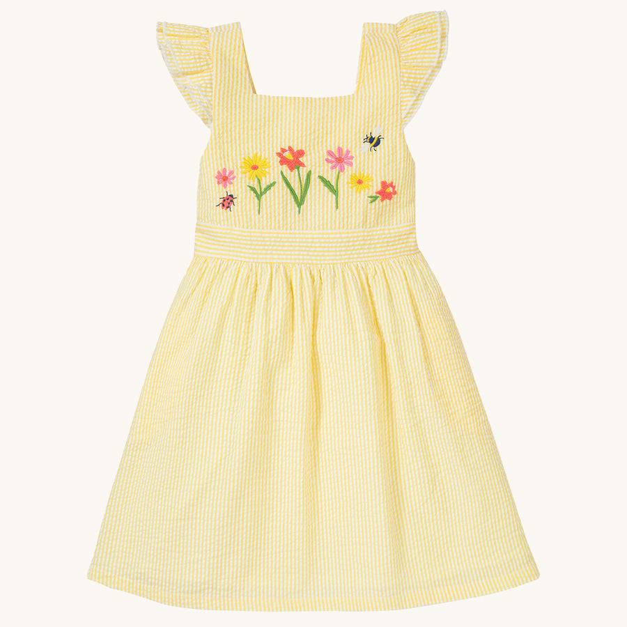 The front of the Frugi Jasmine Dress - Flowers made from GOTS Organic cotton. A light sunshine, yellow and white striped short sleeve dress with adjustable ruffle straps, smocked back, and a gathered waist with waste band. This dress features carefully em