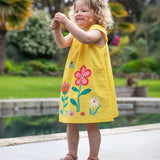 A child wearing the Frugi  Yellow Spot / Flower Lowen Dress.