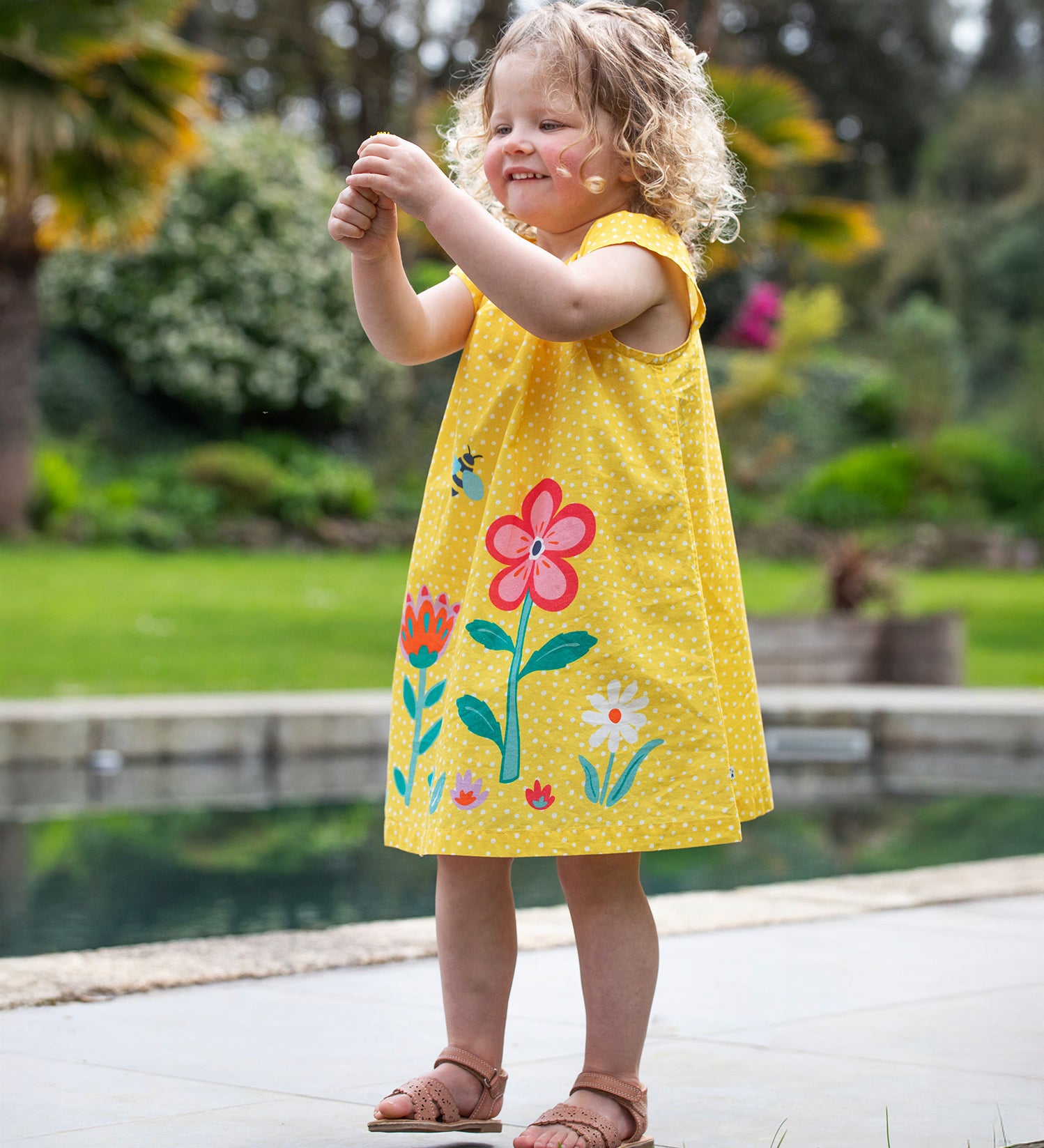 A child wearing the Frugi  Yellow Spot / Flower Lowen Dress.