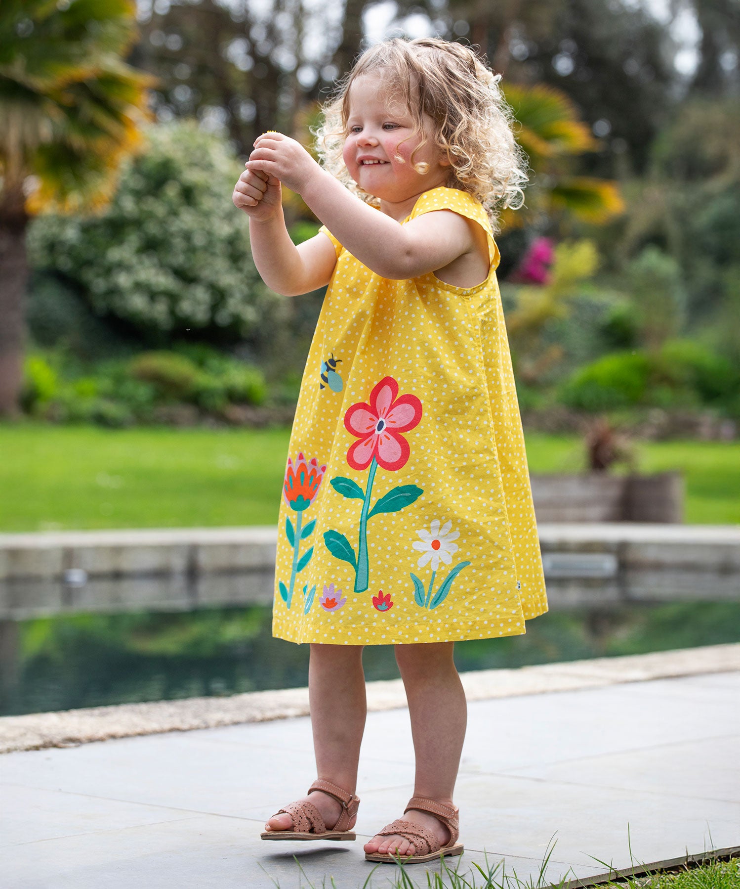 A child wearing the Frugi  Yellow Spot / Flower Lowen Dress.