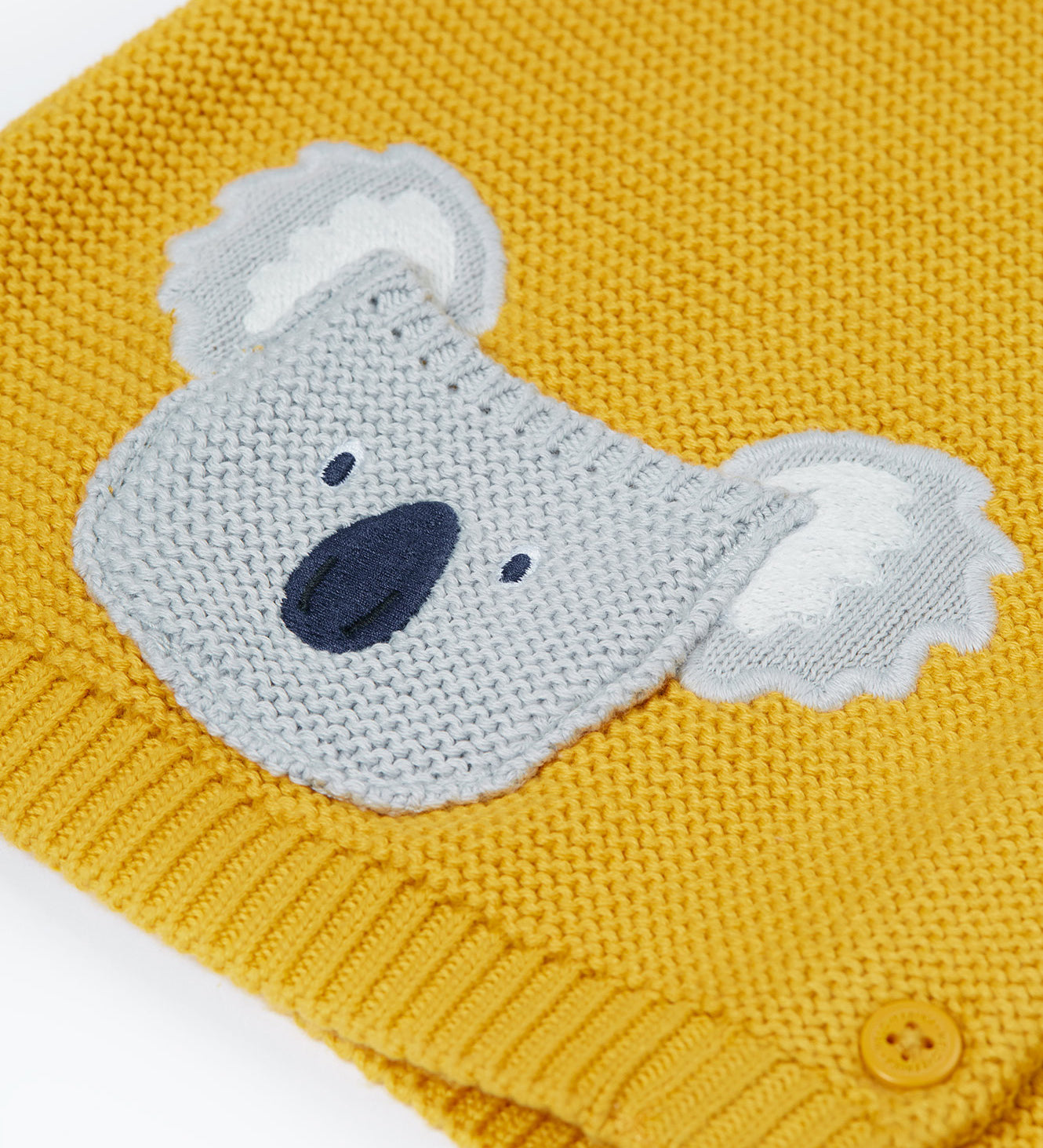 A close up of the organic knitted cotton grey koala bear pocket of the Frugi kids yellow koala cardigan 