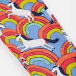 Close up of the Frugi kids over the rainbow leggings. Showing the white horses on top of bright multicoloured rainbows on light blue organic cotton fabric