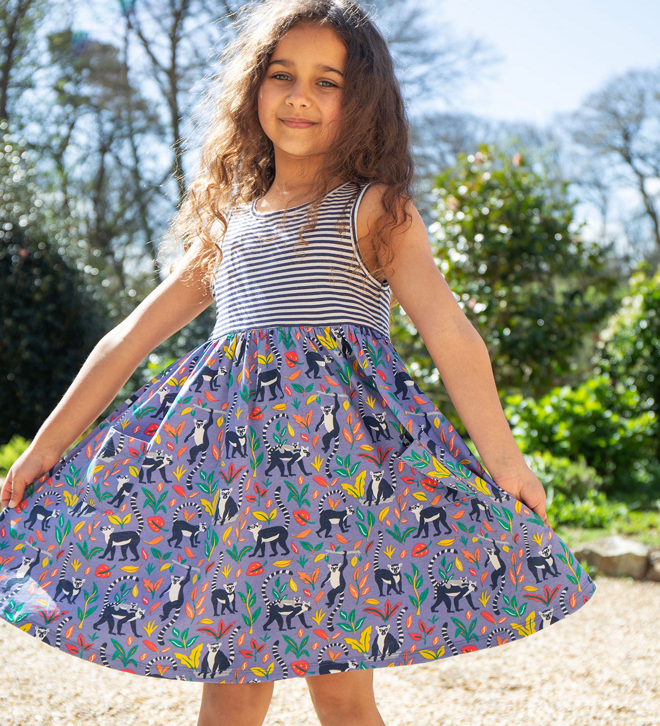 A child wearing the Frugi Summer Holiday Dress with a Lemur Laughs print design