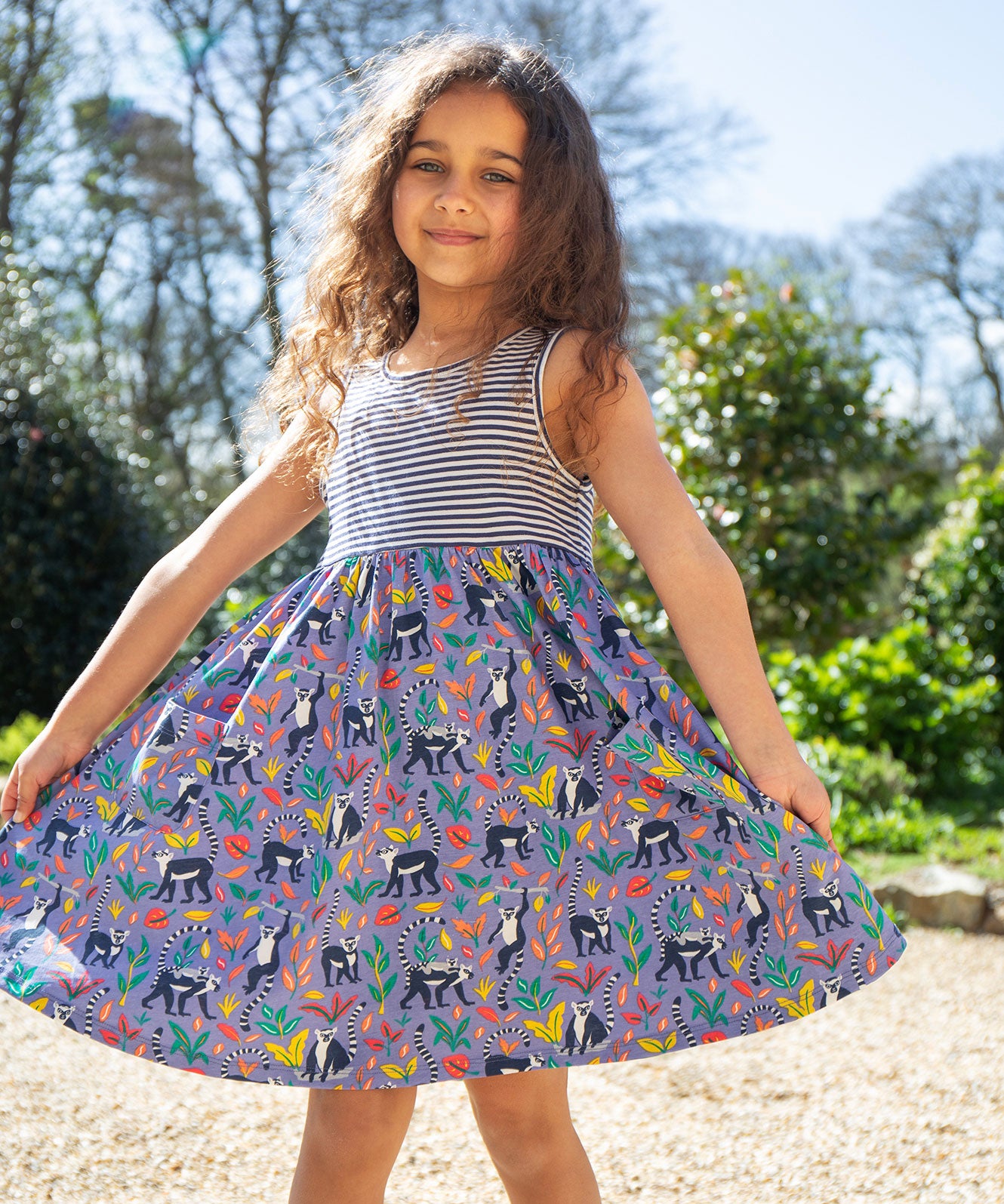 A child wearing the Frugi Summer Holiday Dress with a Lemur Laughs print design