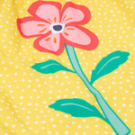 Close up of the Frugi kids lowen flower dress - Showing a pink flower print on yellow with white spots organic cotton fabric