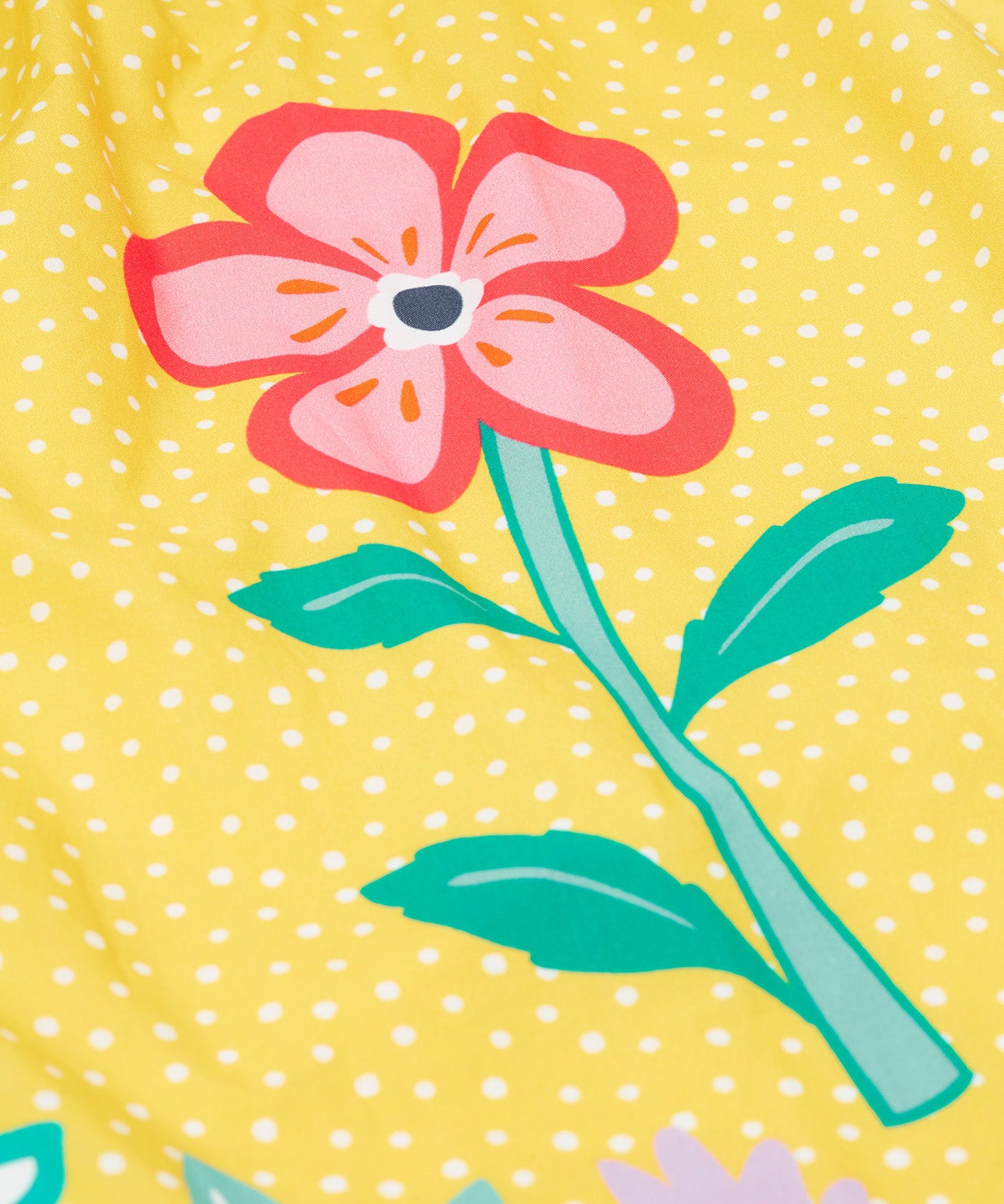 Close up of the Frugi kids lowen flower dress - Showing a pink flower print on yellow with white spots organic cotton fabric