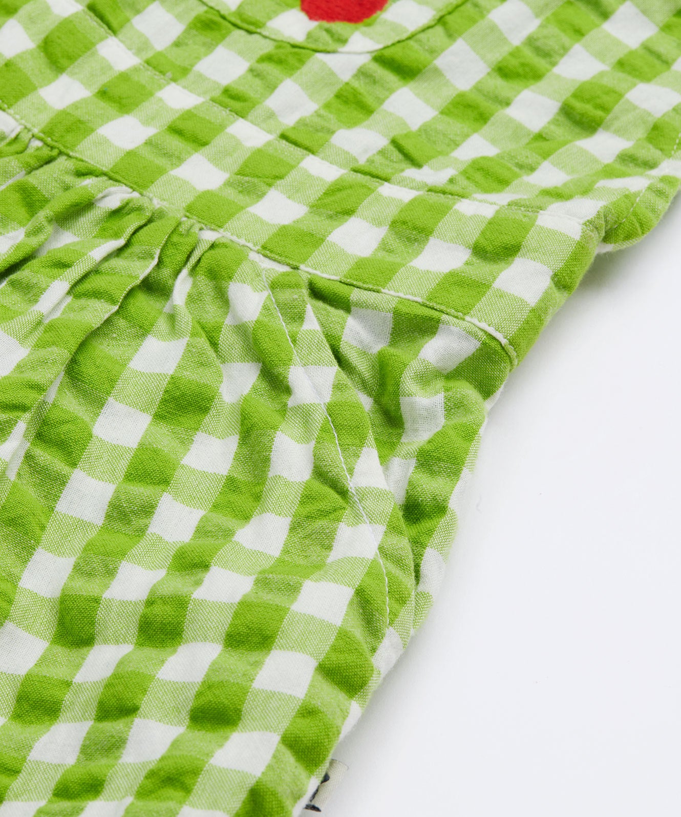 Close up of the Frugi kids macaw ginham, veg culotte dungarees. Sowing the side pocket detail on green and white gingham organic cotton fabric