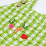 Close up of the Frugi kids macaw ginham, veg culotte dungarees. Showing the embroidery of a beetroot, carrot and apple on the front pouch pocket on green and white gingham organic cotton fabric