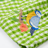 Close up of the Frugi kids macaw gingam birds dress. Showing the bird applique on a green and white gingham organic cotton fabric.